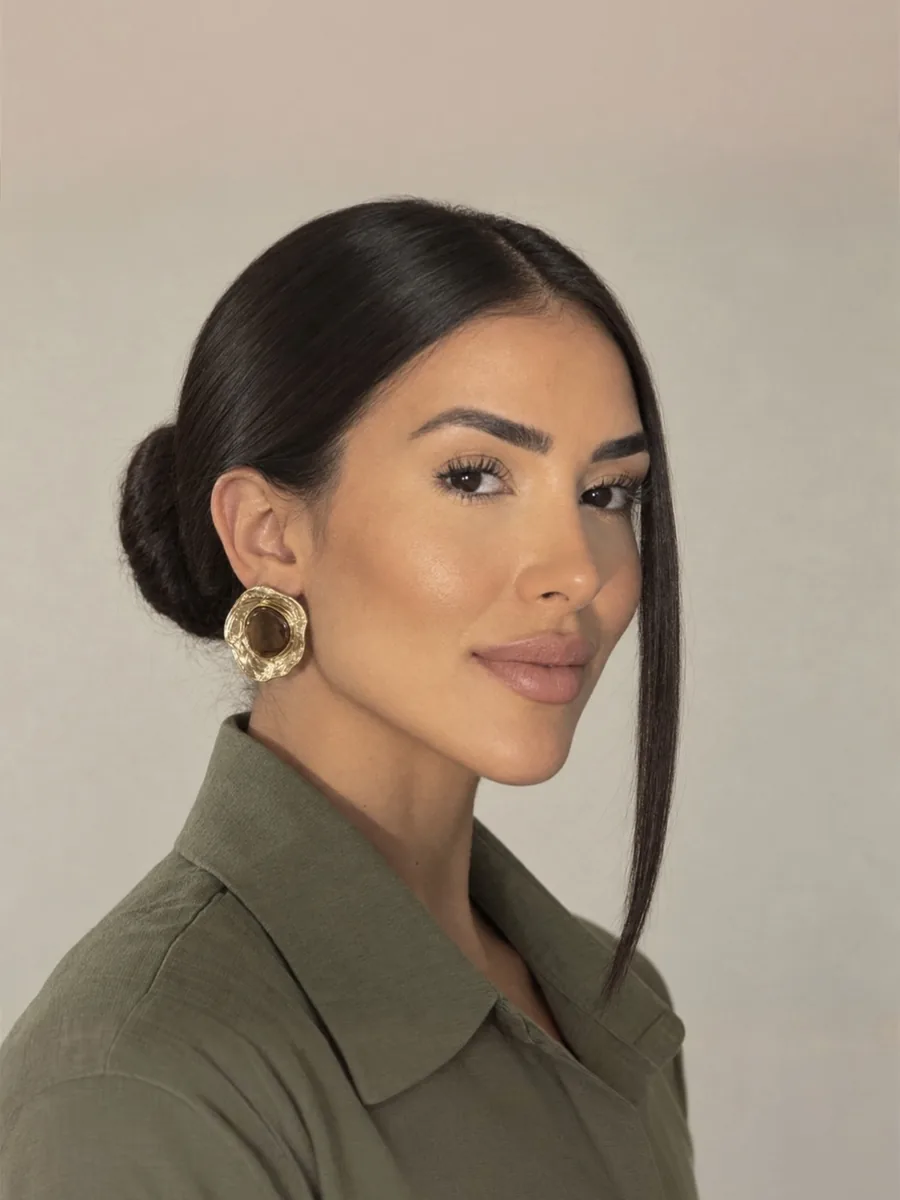 Retrato de perfil de Marcela Freire com cabelo preso e brincos dourados